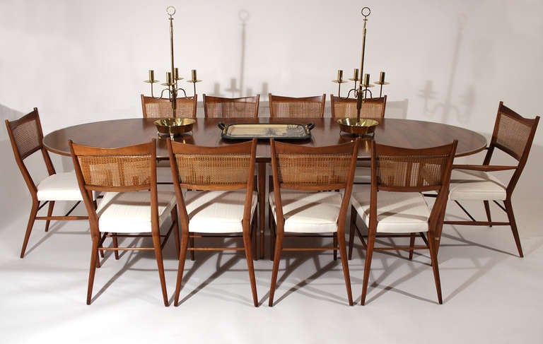 Adjustable walnut & brass dining set designed by Paul McCobb for Directional comprising 10-dining chairs with cane backs and upholstered seats, and extending table. Table includes 6-leaves, each 11