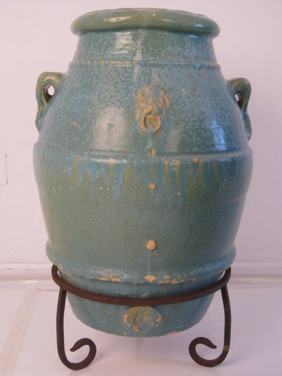 Fantastic and large ceramic urns in original Spanish wrought iron stands. These are massive and heavy. They weigh approximately 80-90 pounds each! Perfect for the garden, front porch or driveway entrance. They are in a sea foam green color which is