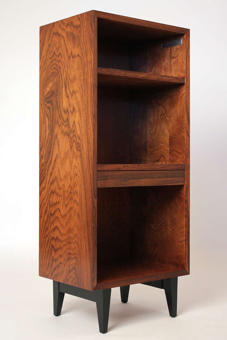 An unusual configuration on this simple design from George Nelson's Basic Cabinet Group for Herman Miller in rosewood. This piece serves as a small bookcase/cabinet or nightstand with a pull out shelf. Excellent condition.