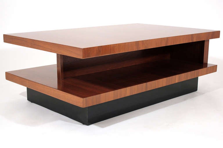 An architectural two-tiered cantilevered cocktail or coffee table in stained walnut with ebonized base designed by California modernist Martin Borenstein for M.B. Designs, Berkeley, CA.

The base of the table is attached to runners which enable