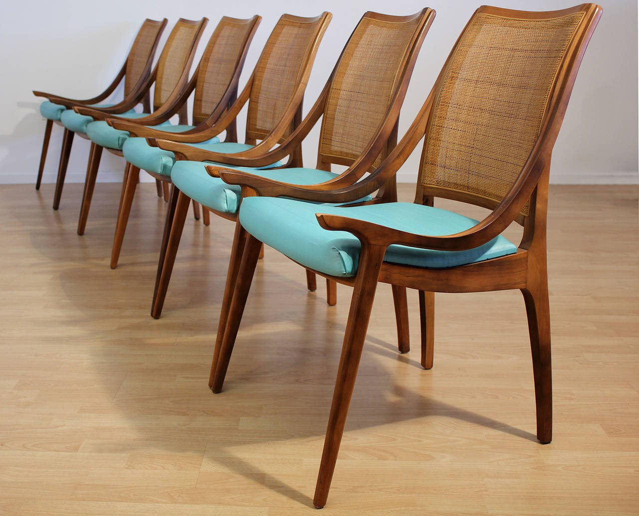 Set of six cane backed walnut dining chairs with original light teal blue seat cushions designed by Richard Thompson for Glenn of California. Chairs are in excellent original condition. A not often seen elegant modern design with low scooping