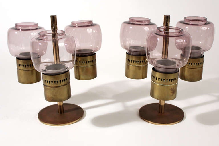 Made in Sweden. Pair of Hans Agne Jakobsson candle holders or hurricane lamps in brass with rose tinted glass.

Dimensions listed are for each.