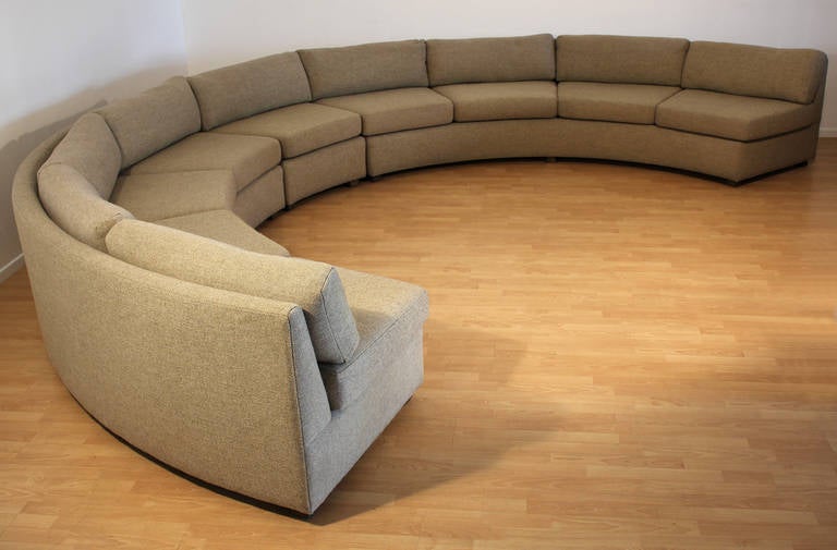 A long modernist 1970s era semicircular sectional sofa consisting of two equally sized curved sections and a single seat that can also be incorporated into the whole. Finished in it's original oatmeal colored textured fabric. The upholstery is in