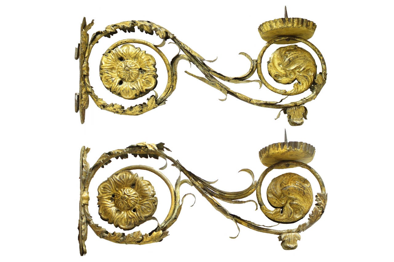 Pair of 18th Century Louis XIV Italian Iron Giltwood Sconces. Exquisite pair of scroll-shaped gilded iron candle sconces with ornately carved and detailed rosettes and foliage through the design. Wear consistent with use and age, losses and breaks