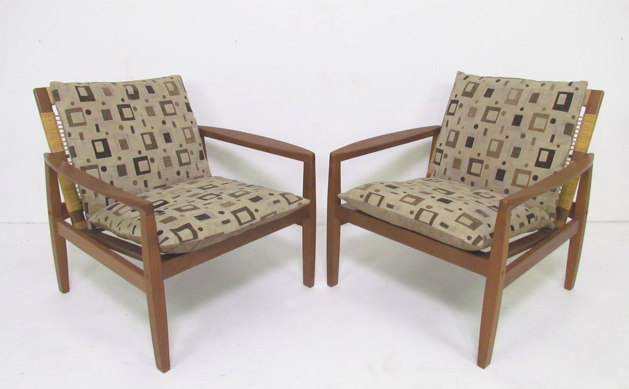 Pair of teak lounge chairs with woven cane backs by Hans Olsen for Juul Kristensen, Denmark, circa late 1950s. 

Cushions, though serviceable, are not original, and we recommend replacing. Can be used with or without a back cushion.