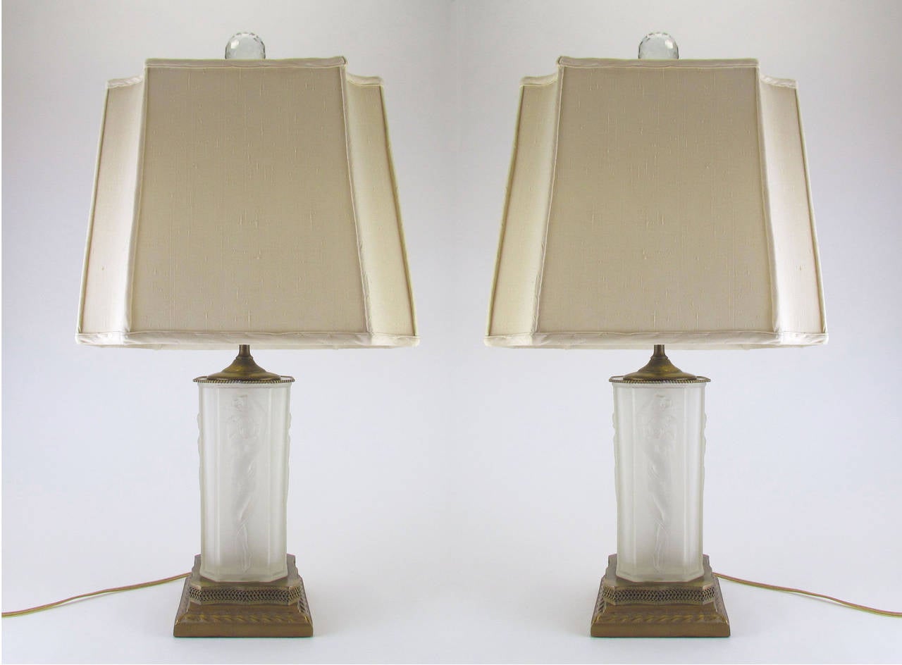 Pair of art glass lamps in clear and frosted glass, with original fittings, in the manner of Lalique, circa 1920s. With hand-sewn silk shades and cut crystal finials. 

Measures: 26.5