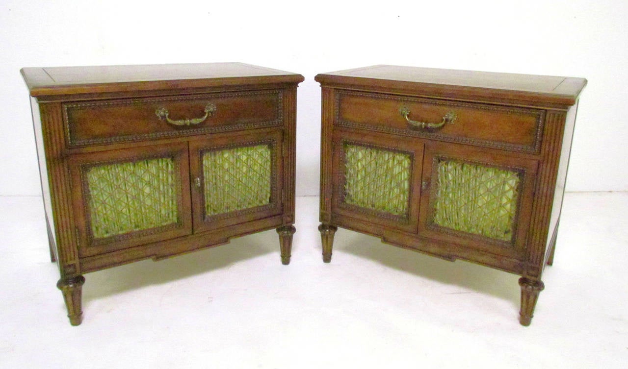 Pair of Mid-Century nightstands in walnut with grilled doors and ornate brass hardware in the Hollywood Regency style by Henredon Furniture.