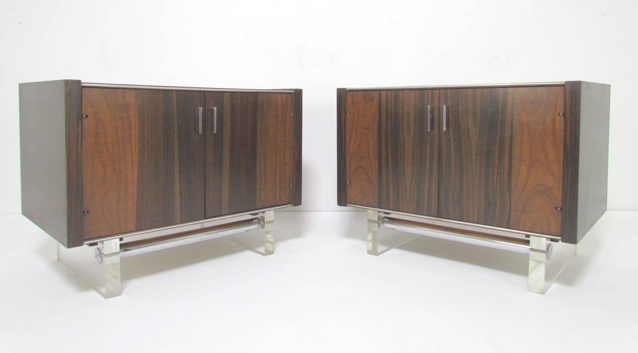 Pair of sleek modernist nightstands by Modernage Furniture Co. in rosewood with Lucite legs and chrome accents, circa 1960s, in the manner of Milo Baughman.