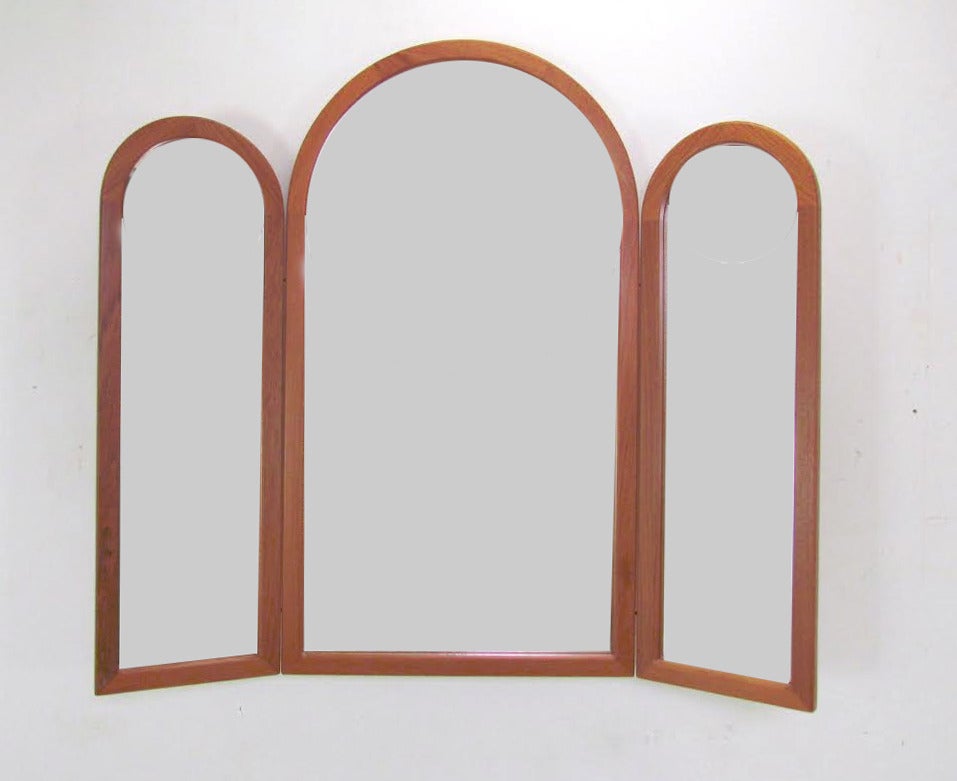 Rare arched teak adjustable tri-fold wall mirror with hinged side panels. Signed with Pedersen & Hansen foil label (model 914), made in Denmark.

When fully open and extended, the mirror is 39
