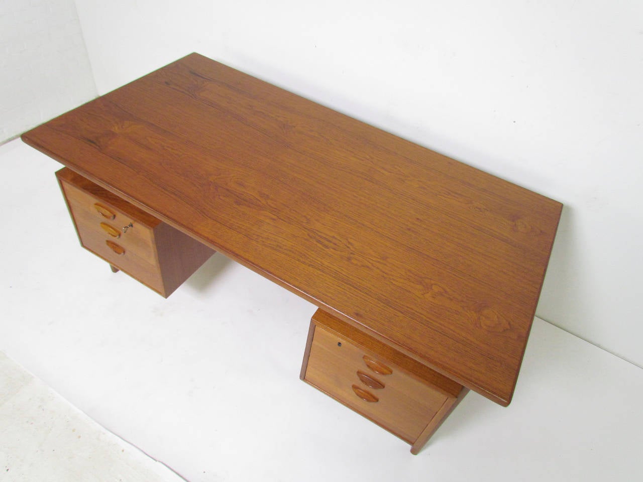 Teak desk by Kai Kristiansen, designed in 1958 for Feldballes Mobelfabrik, Denmark. Six drawers featuring Kristiansen's signature carved handles. Includes original key which opens top drawers on either side. Suspended teak top, and finished back