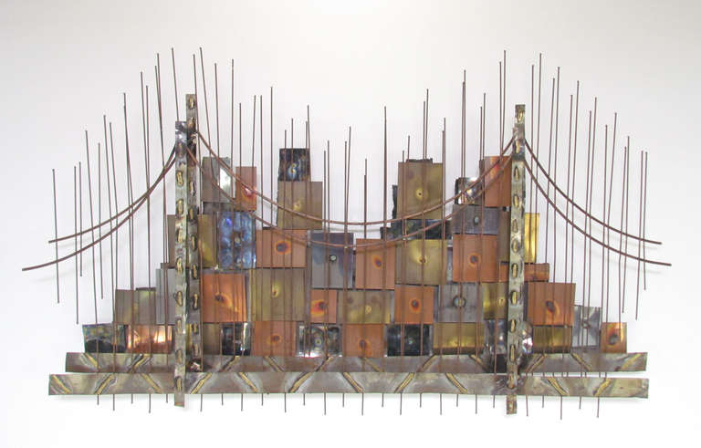 One of a kind spectacularly detailed brazed metal (brass, steel, copper) wall sculpture depicting the sweeping arches and cables of a suspension bridge with a city-scape of mixed metal panels.    In the manner of Curtis Jere, ca. 1960s.