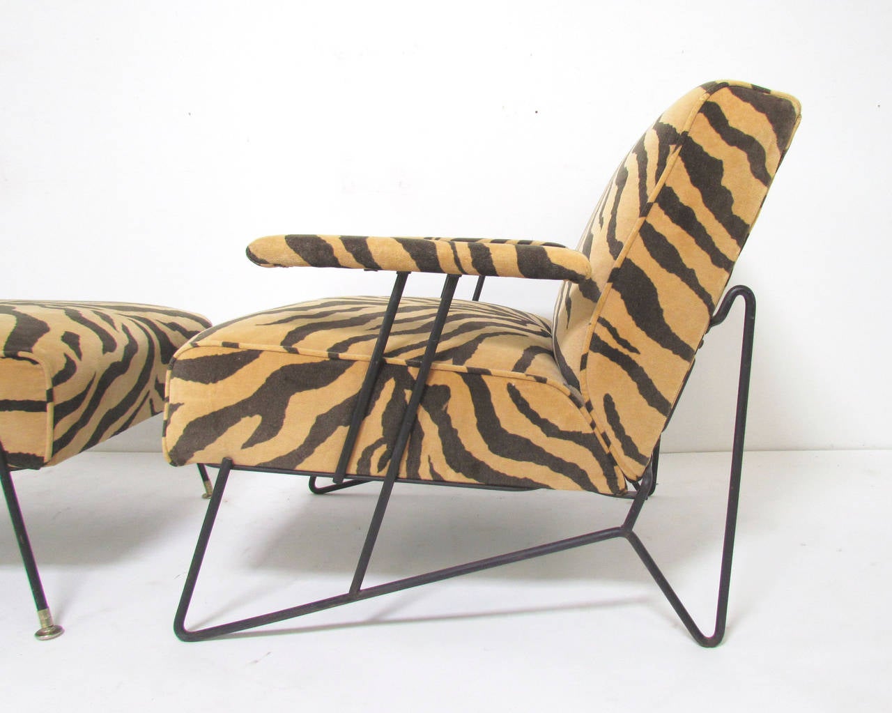 Wrought iron lounge chair and matching ottoman in period tiger stripe upholstery attributed to Dorothy Schindele, circa 1950s.

Chair measures: 26.25