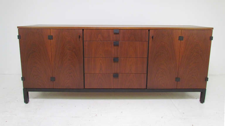 Rare mid-century modern sideboard designed by Milo Baughman for Directional, manufactured by Johnson Furniture co., ca. mid-1960s.  Walnut case with contrasting ebonized base.  This credenza also features black anodized metal hardware and hinges on
