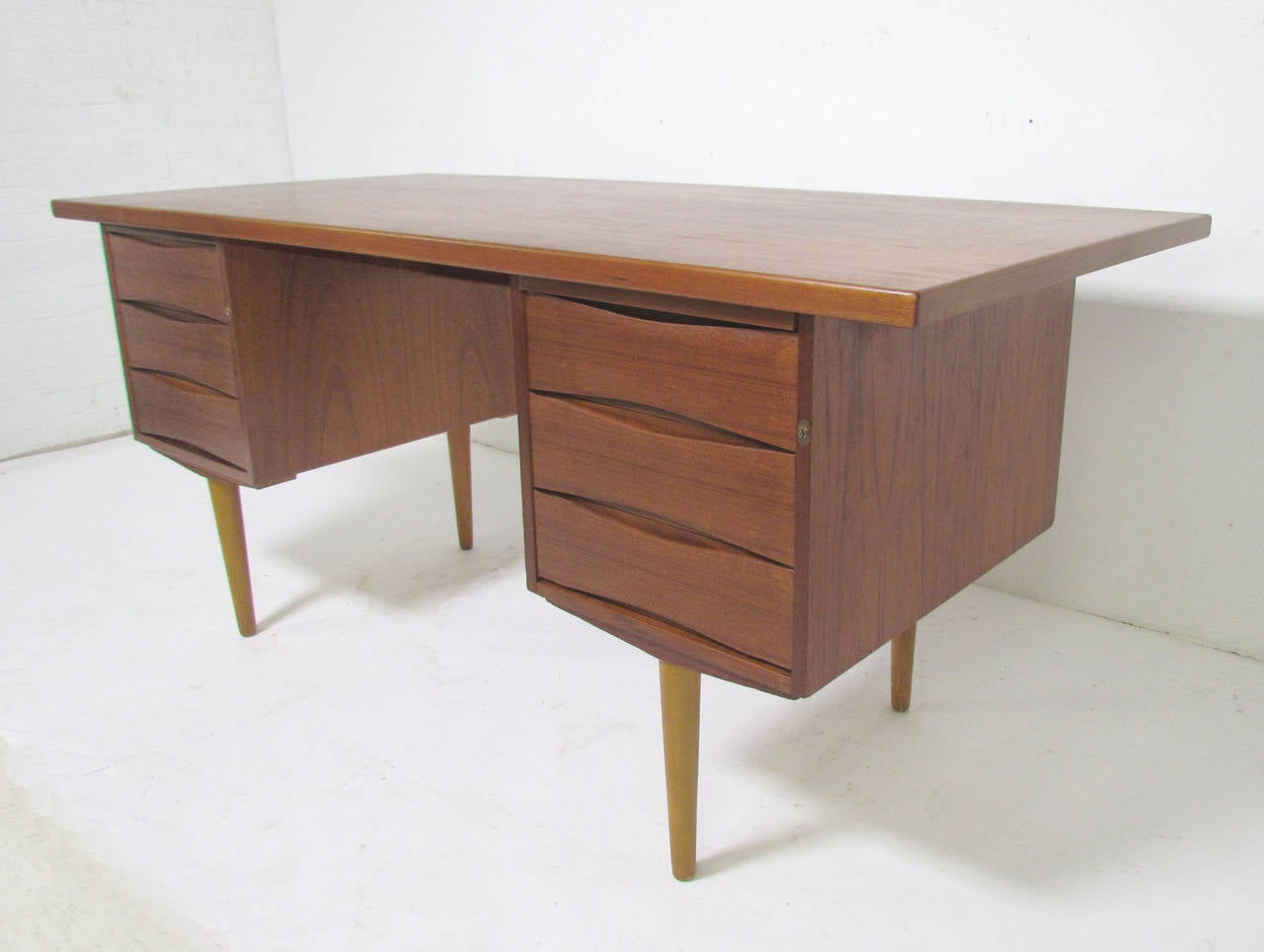 Teak desk by Skeie, Made in Norway for Westnofa Imports. Features inset carved bowtie fronts similar to the designs of Arne Vodder. The right side features a pull-out writing surface and a single (deep) file drawer; the left side features three