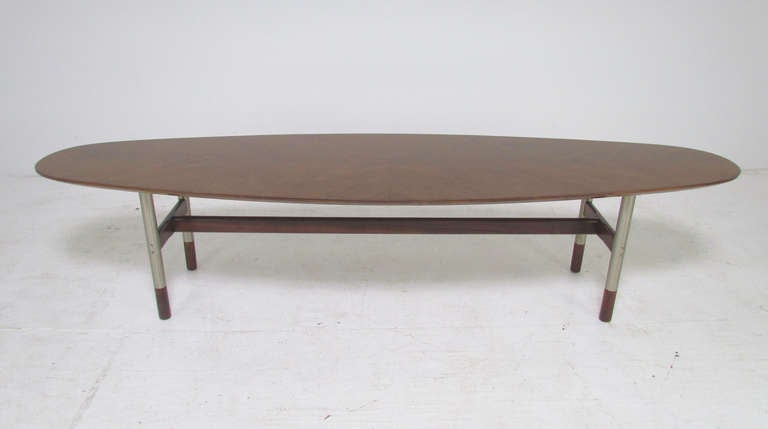 Danish surfboard coffee table with striking book-matched top in transverse  grained teak, and a base of brushed steel legs with rosewood stretchers and foot caps, ca.1960s.  Unmarked, the base is identical in design to many cased pieces by Arne