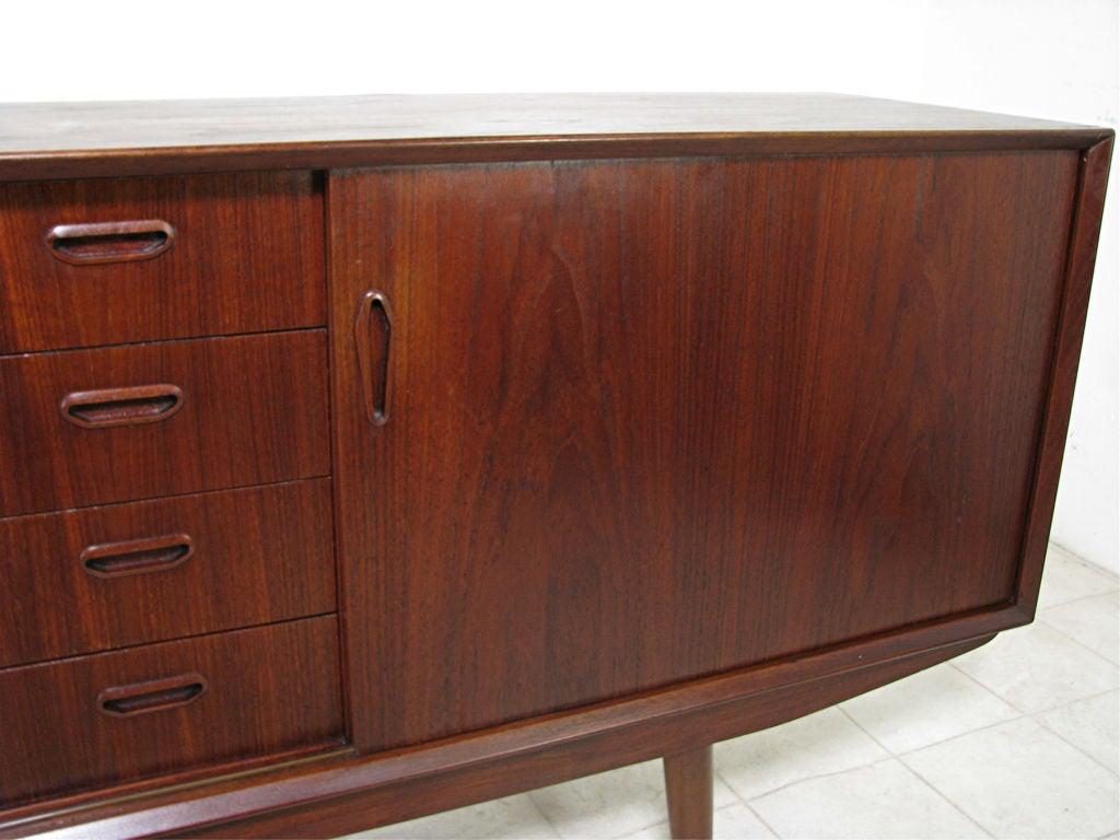 Long low Danish teak credenza by Sven Ellekaer for Jensen & Molholm, ca. early 1960s.   Deep dark-red patina with highly figured book matched door fronts, teak lined interior including drawers.   Finished back, can float in a room if desired.