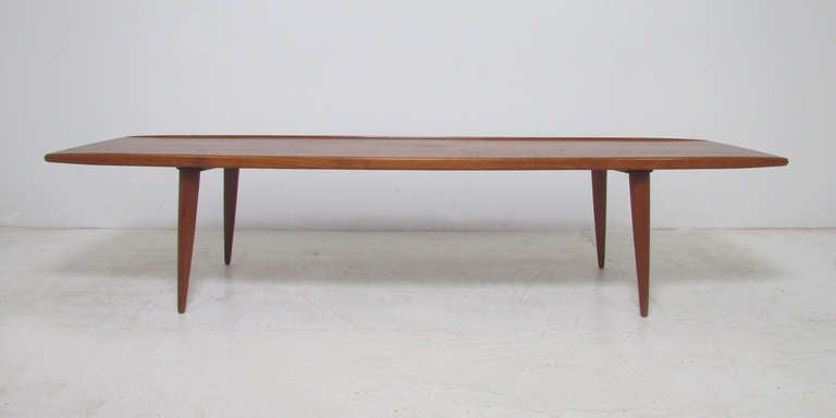 Extra long six foot teak coffee table with sensually carved side rails reminiscent of the designs of Grete Jalk and Finn Juhl.  Extremely fine craftsmanship features gentle tapering at either end.  Made in Denmark, imported into the U.S. by MM