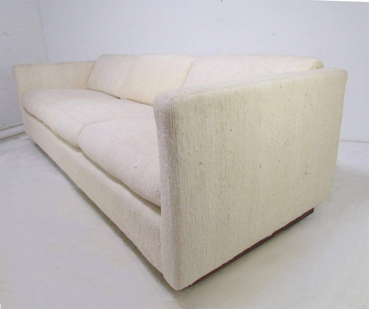 Classic modernist three-seat tuxedo sofa floating on a walnut base supported by casters, signed by Milo Baughman for Thayer Coggin, circa 1970s. Original Haitian cotton upholstery.

Measures: 88