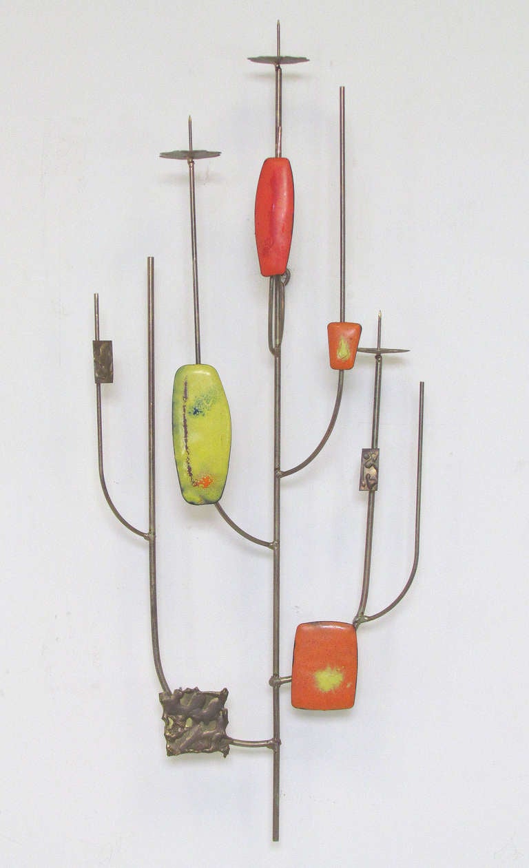 Decorative wirework wall sculpture consisting of brass rods and elements, with enameled plaques, circa 1960s, in the manner of Curtis Jere. Three spikes can hold a candle if desired.