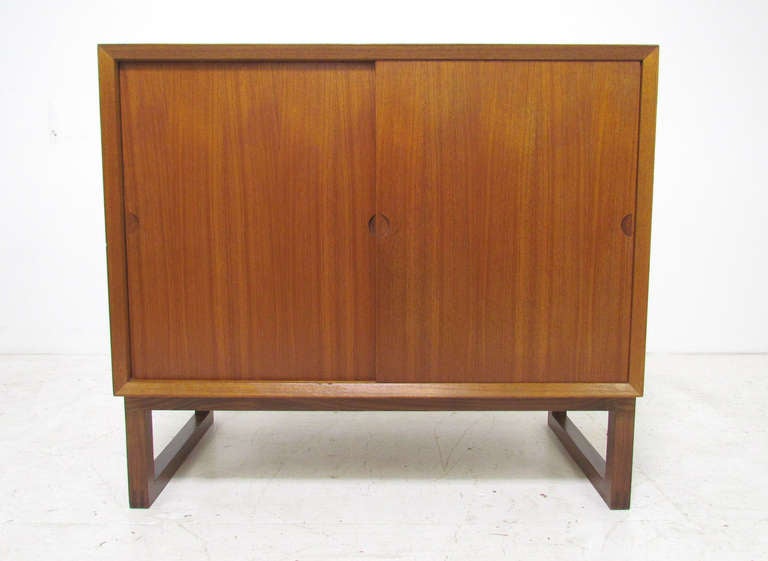 Compact Danish teak two-door chest by Poul Cadovius ca. 1960s.  From a modular wall-mounted Cado system, fitted for use with with original Cado base (a cataloged option).   Base is rosewood, cabinet sits atop it via a dowel system.    Features a