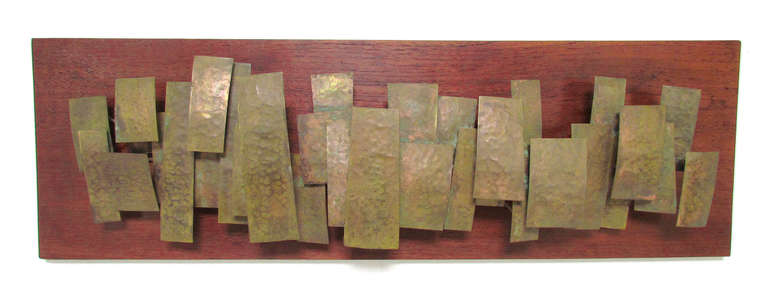 Three dimensional wall sculpture ca. 1960s by Gloucester, MA artist George Edward Lane.  Patinated, hammered brass block forms suspended in relief on a solid teak panel of boat decking.