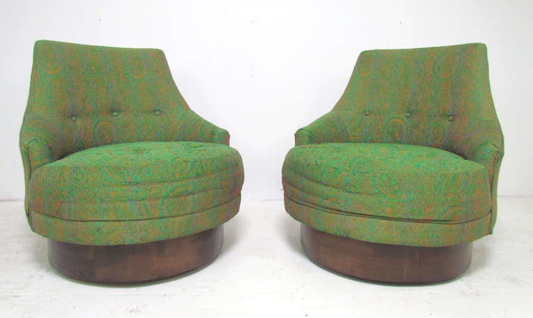 Pair of swivel lounge chairs on oversized walnut bases ca, 1960s by Adrian Pearsall for Craft Associates.   

These classic mid-century lounge chairs swivel from side to side, gently returning to center position when sitter rises from the chair. 