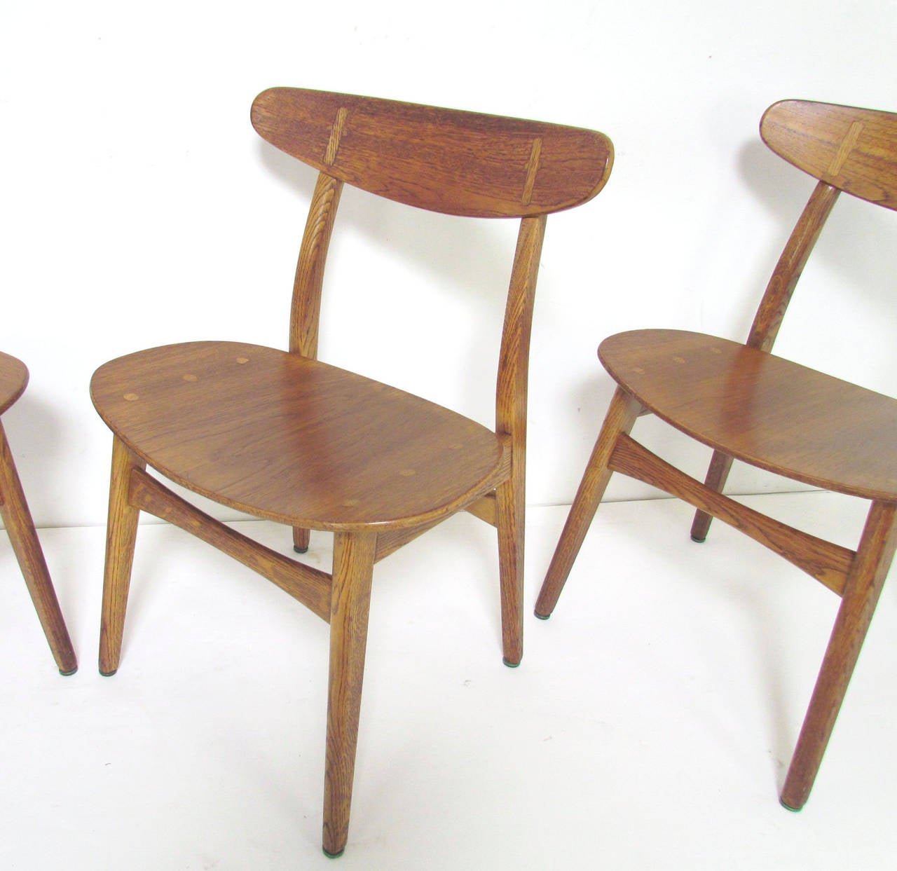 Set of four Danish dining chairs, model CH 30, designed by Hans Wegner for Carl Hansen, circa 1960s. 

Teak seats and seat backs with oak inlay and legs, original aged patina. Original owner had custom cushions created for these which are still