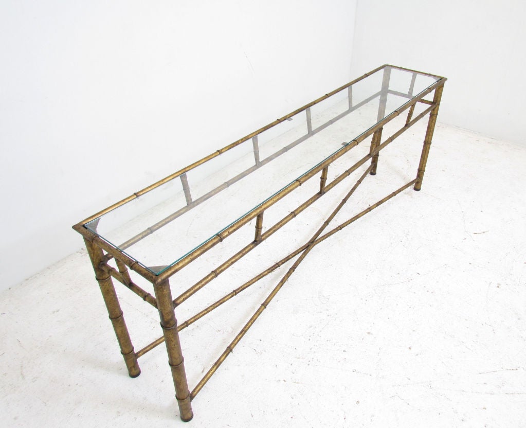Glass topped console table in faux bamboo, metal-work frame with X-base, with an antiqued gilded finish.