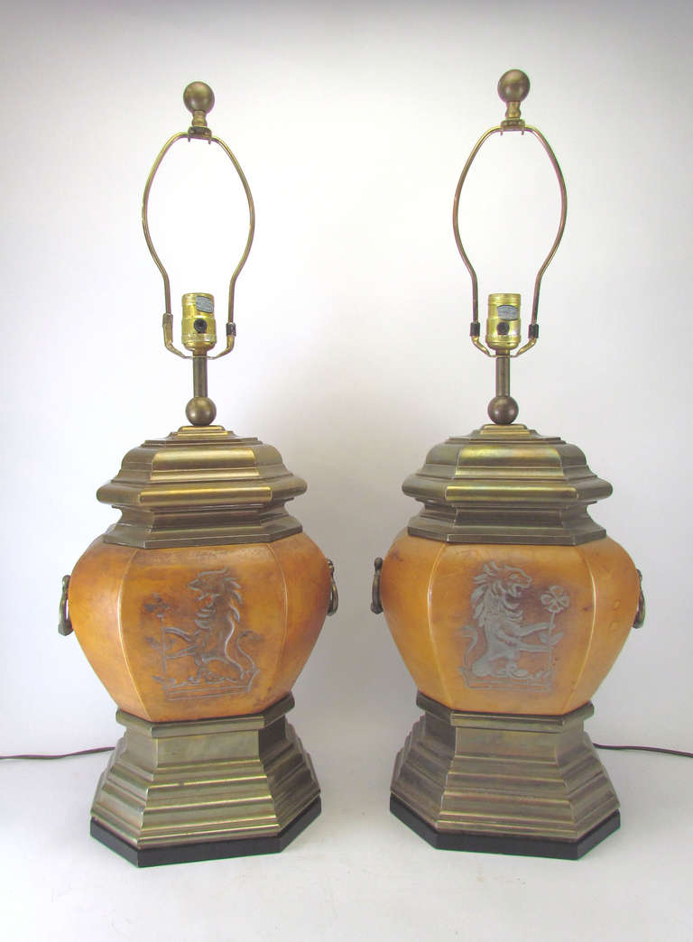 Pair of table lamps by Chapman Manufacturing Co., clad in leather embossed with a gryphon design.  Slight variation between the two due to the handmade nature of the leather elements.    Same design on reverse of both, an attractive  feature for