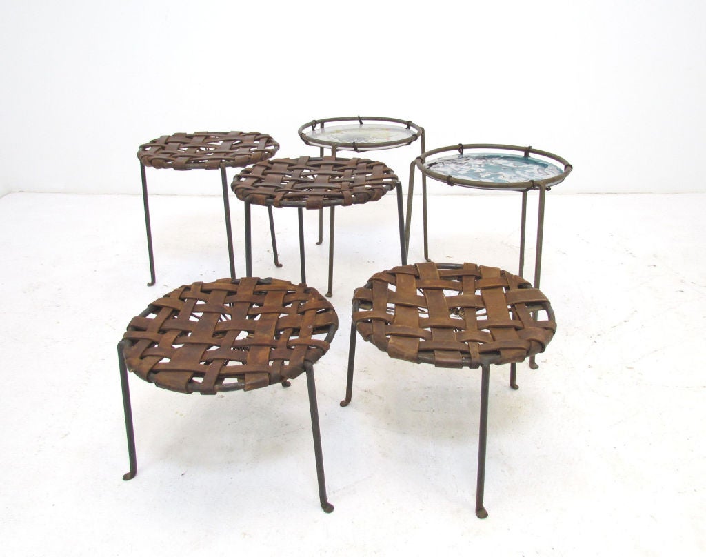 Rare studio craft made collection of stools and tables by Lila Swift and Donald Monell, ca. 1950s.  The stools are constructed of leather straps stretched upon welded steel frames.   The tables are enameled steel suspended with leather lacing.  