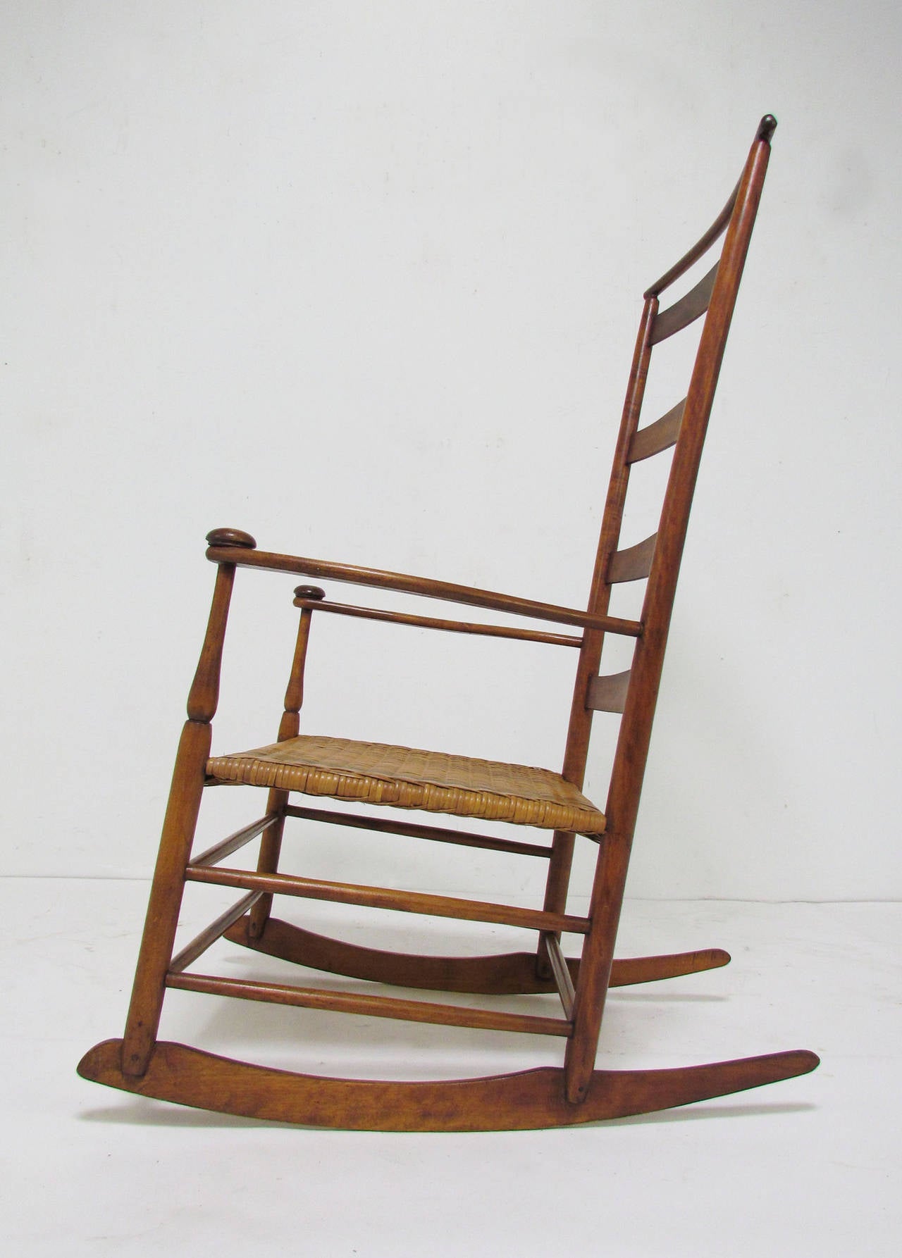 Original Mt. Lebanon, NY Shaker rocking chair, circa 1890s. Stamped # 7, the largest adult size. In stained maple with shawl bar above the top back rest.