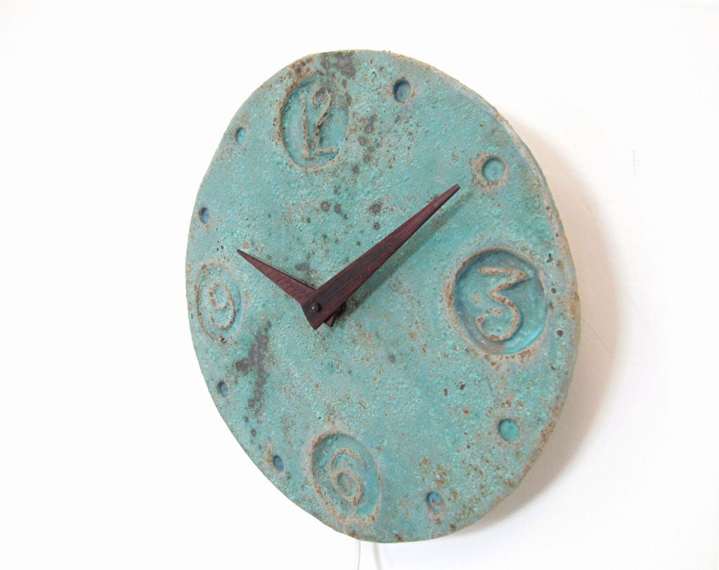 Mid-century hand built studio art pottery electric wall clock with solid rosewood hands.  Attractive curdled turquoise glaze with inset stamp formed numbers.  With original mounted electric works.