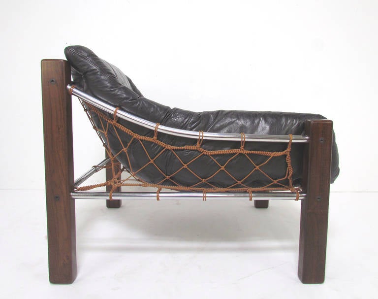 Low slung leather lounge chair with Brazilian rosewood (jacaranda) legs, chromed steel stretchers, and innovative netting support, designed by Jean Gillon for Italma, Wood Art, Brazil, ca. 1960s.