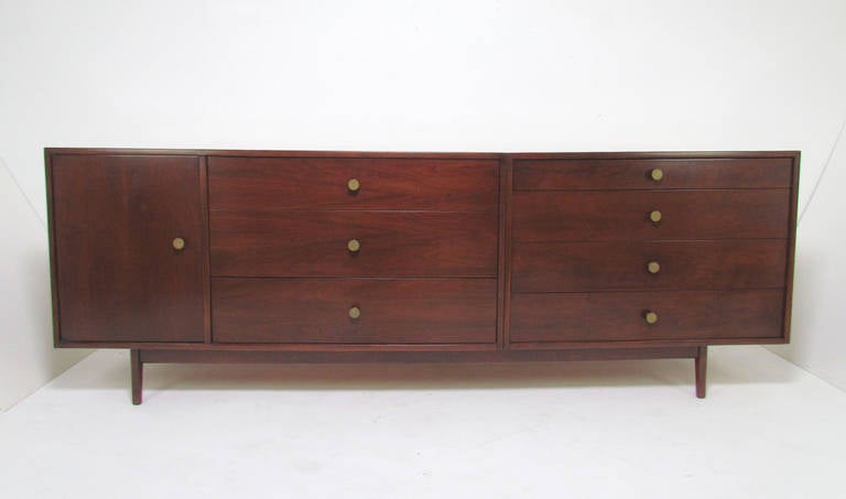 Extra long 7.5' credenza, consisting of two walnut cabinets mounted on a platform base, by Jens Risom, circa 1960s. Could also serve well as a dresser.

Both cabinets signed with Jens Risom Design Inc. label.