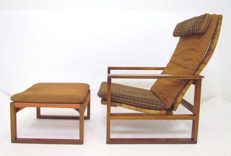 Mid-century Danish teak and oak high back lounge chair with matching ottoman, designed by Borge Mogensen for Fredericia Furniture, ca. mid-1950s.   This version, with cane seat and back support, is an early model.      Two-position reclining seat. 