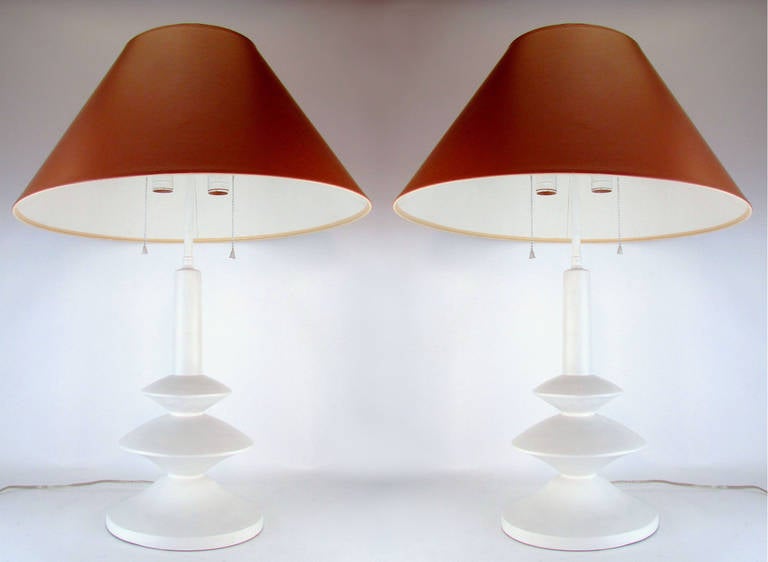 Pair of 1970s era lamps in smooth plaster, after a design by Alberto & Diego Giacometti for Jean Michel Frank. Each lamp with original shades, finials, and (adjustable) double sockets. The shade height is also adjustable.

At highest setting,