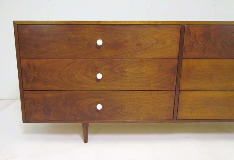 Mid-century modern long low chest of drawers in walnut with white ceramic ball pulls, in the manner of the Declaration Line designed by Kipp Stewart for Drexel.   Unmarked, appears to be custom.    Ca. 1960s.