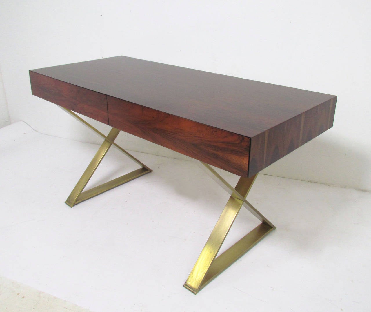 A very fine campaign desk by Milo Baughman in rarely-seen rosewood, X-base legs with bronze finish.  Unlike other models, this design features drawers that are flush mounted to the desk top, with no visible handles.  Drawers open by finger pulls