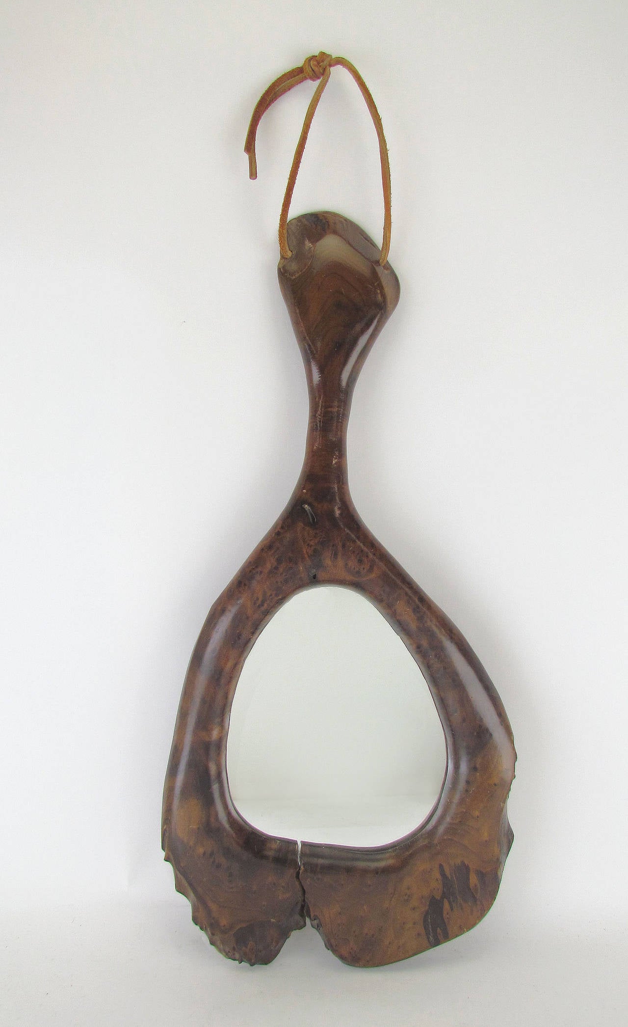 One-of-a-kind organic hand-carved burl wood hand mirror with leather thong for hanging, circa 1970s. A wonderful example of Hippie-era handcraft. Can be used as a hand-held vanity mirror or wall hung for dramatic effect.

24.75