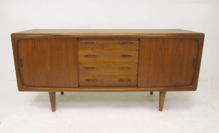 Danish teak credenza by HP Hansen, circa 1960s. Carved, solid teak framework borders two sliding door panels. Middle section with drawers, both sides feature adjustable shelving.