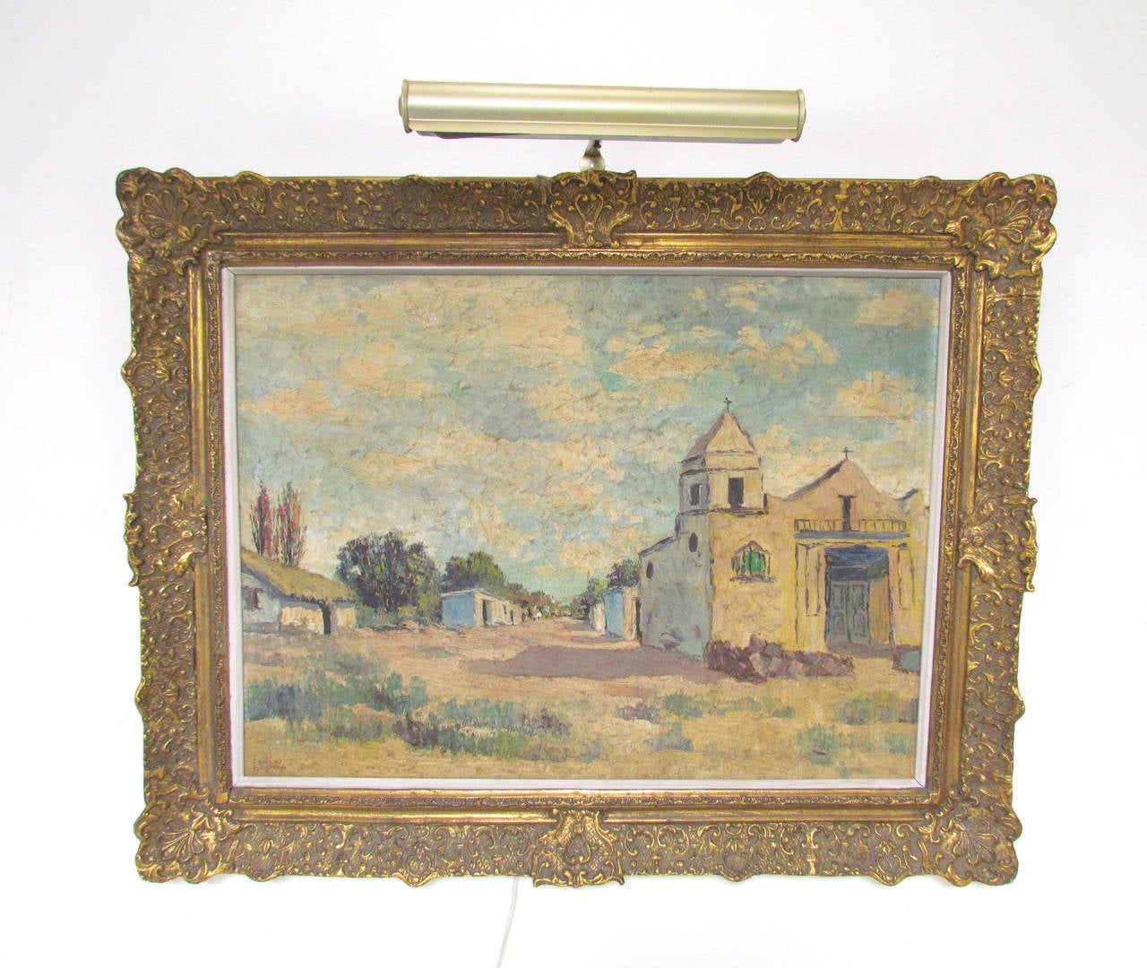 Striking palette knife oil painting of a village in Argentina, circa 1950s. Classically framed large-scale work depicting a Mission and street view by known Argentinian itinerant artist Carlos Brondo. Has an almost Southwestern flair.