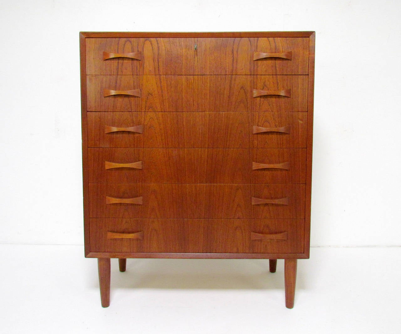 Danish teak chest of drawers with outset bowtie pulls. Includes key for top drawer lock.