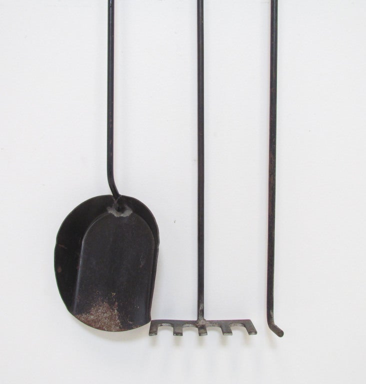 Striking set of wall-hung fireplace tools, handcrafted, ca. 1960s with extra long handles that allow for safe fire tending and a sinuous mantel-side appearance. Mounted on rosewood pegs, the set consists of a poker, ash shovel and coal rake.   40