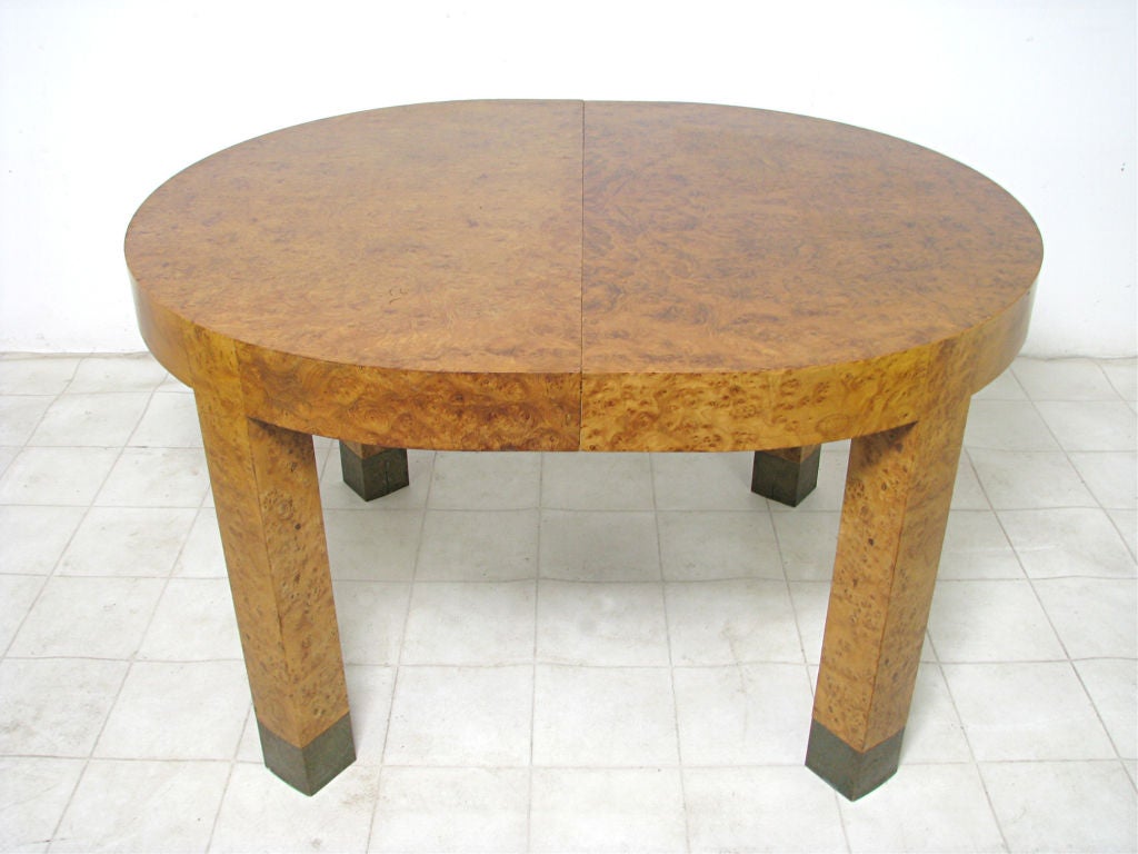 Impressive olive burl wood Parsons style dining table, in the manner of Milo Baughman. Rare oval shape just over four feet long without the leaves, expands to eight feet long with all three leaves.   Legs capped with brass sabots.    <br />
<br