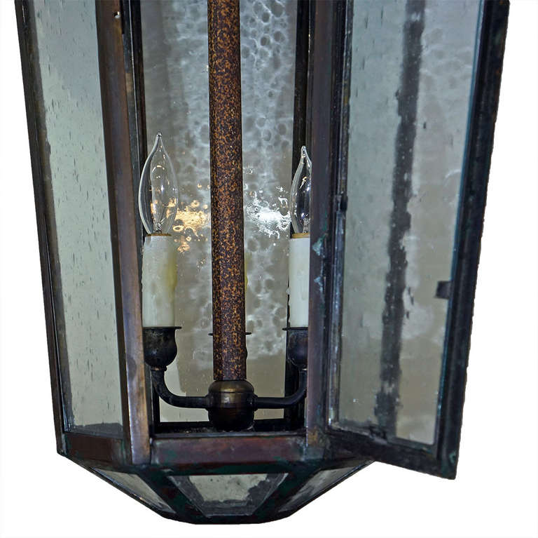 Very large English-style hanging lantern. Appears to be made of copper as seen in minor scratch visible in Image 4. Desirable aged patina throughout with worn green paint on base of fixture. Hexagonal structure with beautiful bubble glass. Wired for