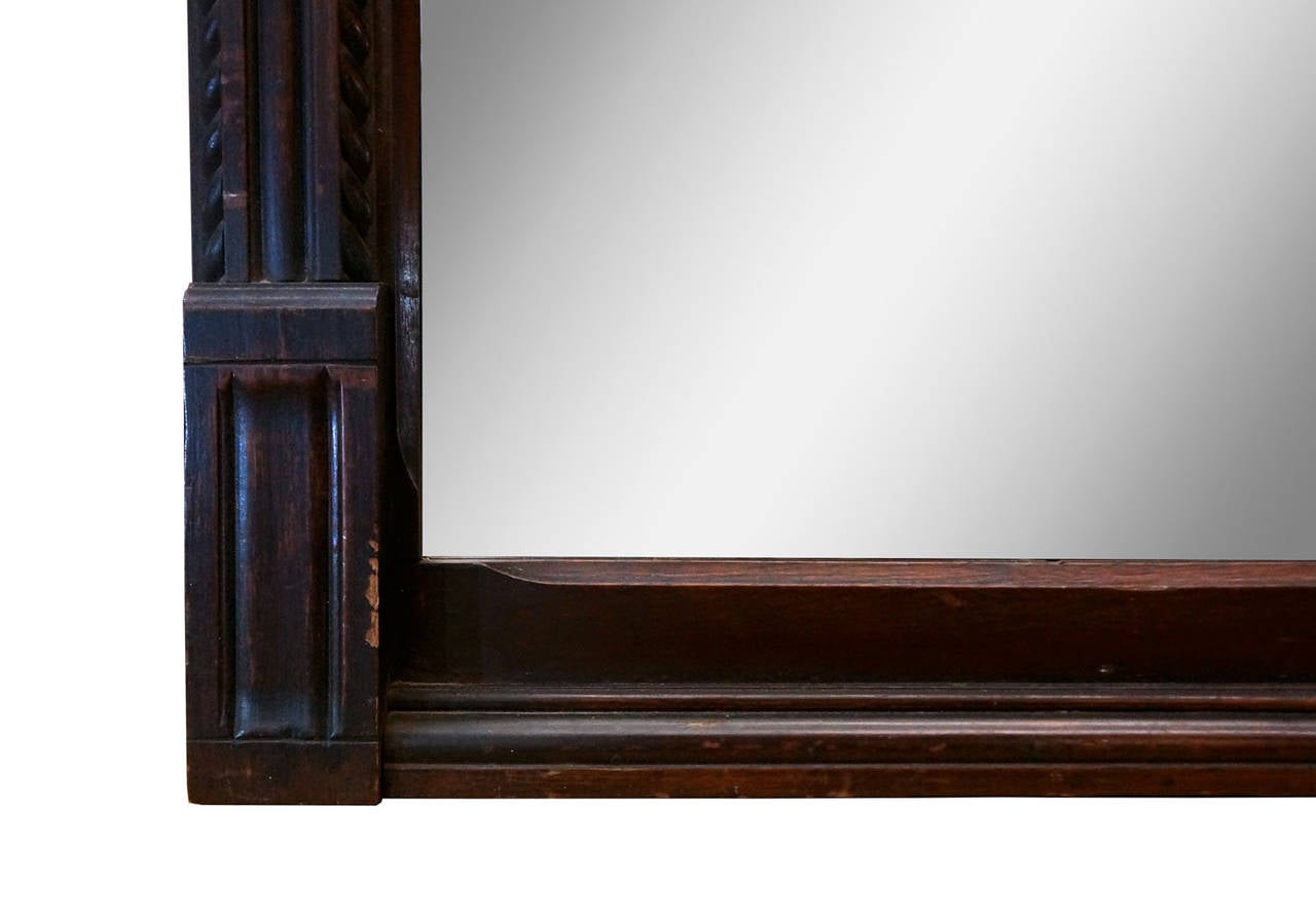 Handsome console mirror from carved mahogany. The crown of the frame has two beveled mirror inserts with heavy patina. The main mirror is a recent addition to this old frame and is in excellent condition. The body of the Regency-style frame has