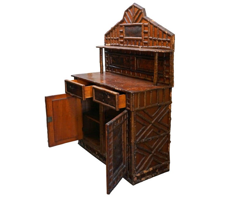 Excellent example of Adirondack furniture with supreme detail. Handmade piece that has stood the test of time with minor losses and scratches. Two drawers and two cabinet doors for storage of personal items. Extensive use of tree bark detail