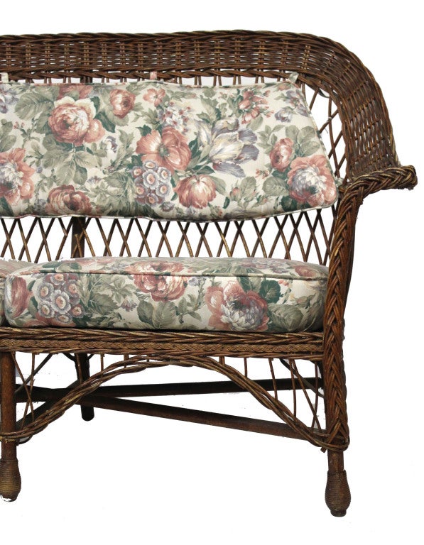 Wicker settee with natural stain and floral covered cushions.

*Not available for sale or to ship in the state of California.