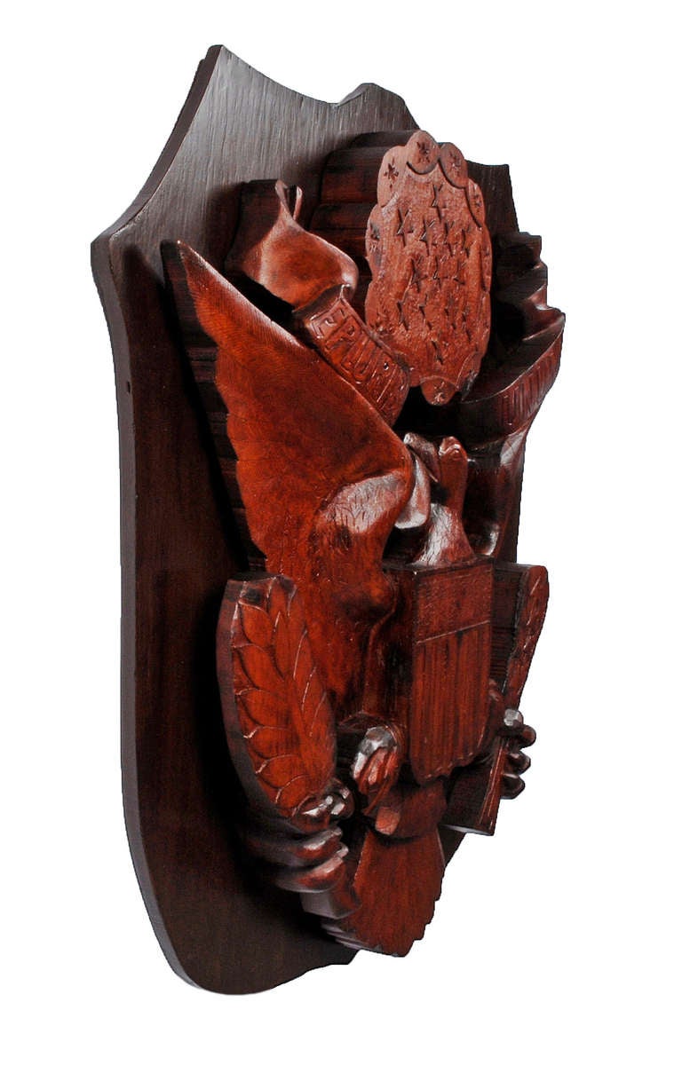 A majestic carved eagle plaque on a shield shaped mount. Beautifully executed the eagle is made out of Redwood and there is a label on the back stating, 