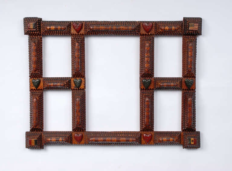 Wonderful tramp art flag frame with an excellent surface. Carved painted flags are displayed in each corner along with carved red and green hearts adding further embellishment. Circa 1900.